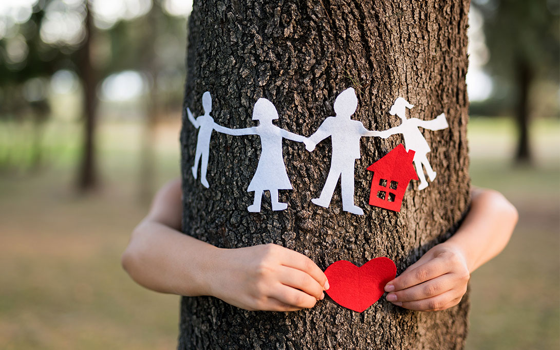 child hugging tree with paper dolls