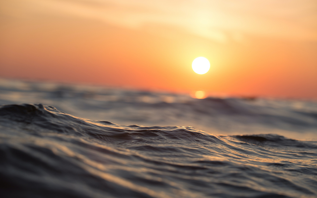 Photo of the open ocean beneath a dusky orange sky (Photo by Sebastian Voortman / Pexels)