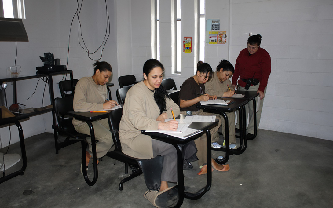 Female inmates in classroom wearing tan and black