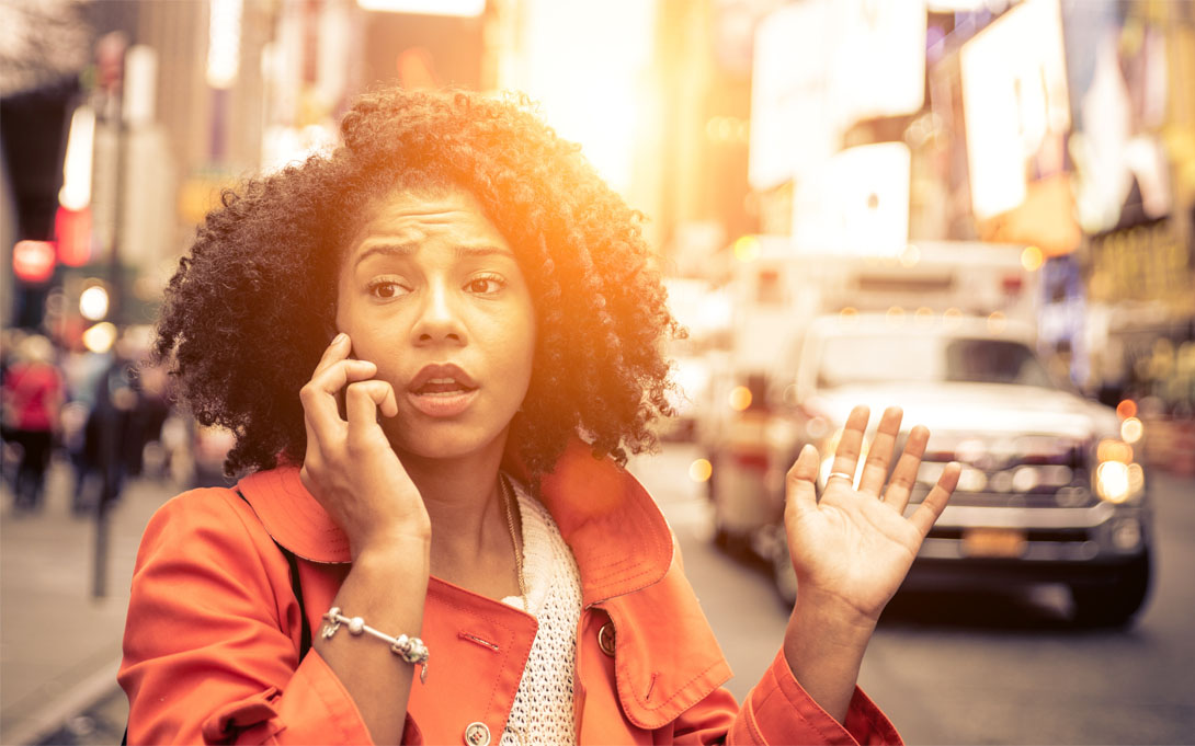 Woman outside of her car on her cellphone at traffic intersection