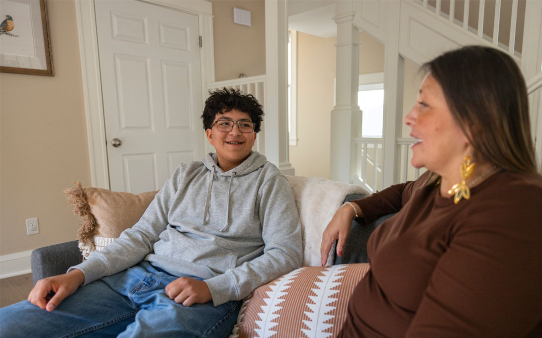 Boy sitting on the couch next to his mom