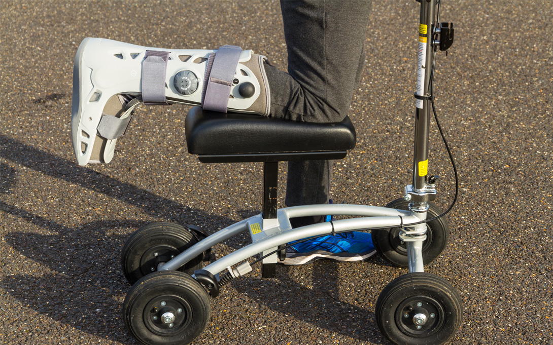 Image of knee scooter with a person's knee and leg in boot cast 